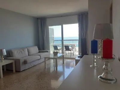 a living room with a white couch and a balcony at Suitur apartamento primera linea mar vistas playa in Canet de Mar