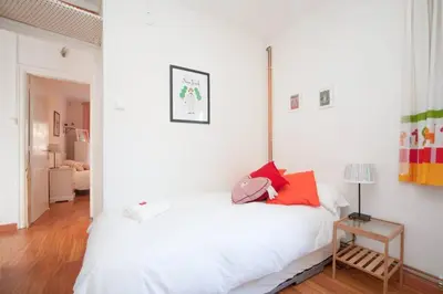 a white bedroom with a white bed and a lamp at Apartamento Parc Güell in Barcelona