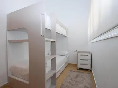 a white bedroom with a bed and shelves at La Platgeta · La Platgeta · Ideal family apartment, with private terrace in Vilassar de Mar