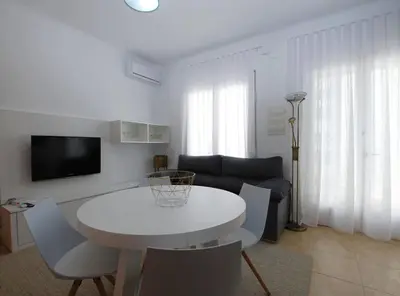 a white living room with a white table and chairs at La Platgeta · La Platgeta · Ideal family apartment, with private terrace in Vilassar de Mar