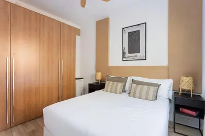 a bedroom with a white bed and a wooden cabinet at Stylish 3 Bedroom Apartment in Barcelona