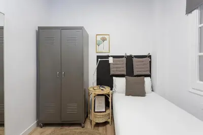 a small bedroom with a bed and a cabinet at Stylish 3 Bedroom Apartment in Barcelona