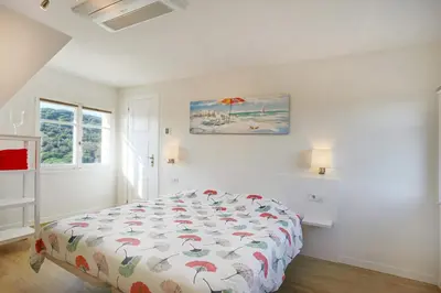 a white bedroom with a bed with a colorful comforter at Homestay Villa Estrella - Costa Brava in Calella