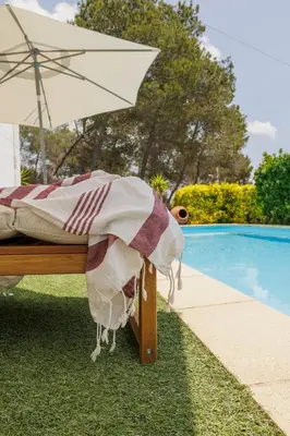 a bed with an umbrella next to a pool at CIM Apartments in Olivella