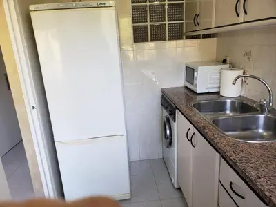 a small kitchen with a sink and a refrigerator at Apart.3 habit.mar-mont. AC-Terraza-ascensor-parking in Calella
