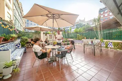 a group of people sitting at a table with an umbrella at Fabrizzios Terrace Hostel in Barcelona