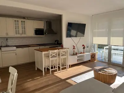 a kitchen with white cabinets and a table with a counter at Apartamento Bea Beach in Badalona