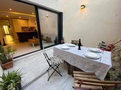 a table with chairs and a bottle of wine on a patio at Beautiful apartment 5 minutes walk to the beach in Caldes d'Estrac