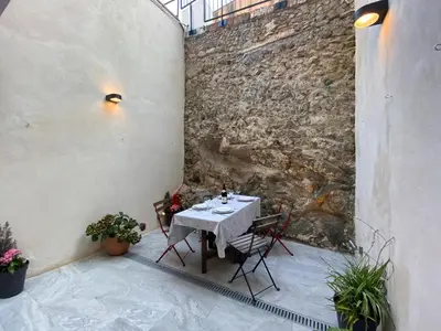 a table and chairs on a patio with a stone wall at Beautiful apartment 5 minutes walk to the beach in Caldes d'Estrac