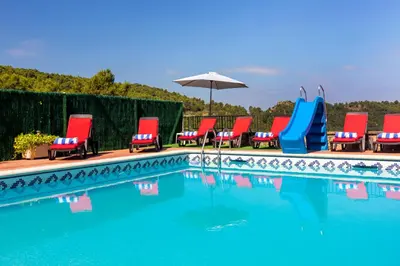a group of chairs and an umbrella next to a swimming pool at 8 to 10 Sleeps Private Pool Villa & BBQ Near Barcelona in Rocafort