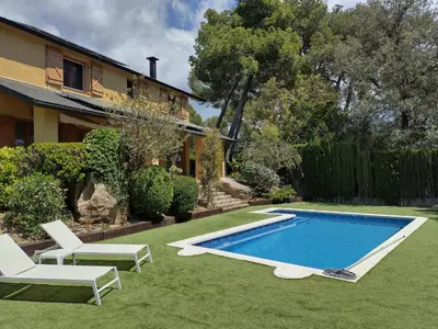 a yard with a swimming pool and two chairs and a house at Casa Feliz in Sant Cebrià de Vallalta