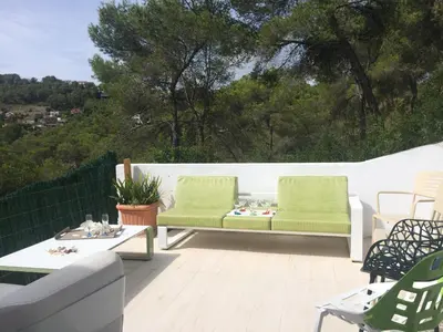 a patio with two green chairs and a table at Villa Paradise , playa privada a 10 minutos de Sitges in Sant Pere de Ribes