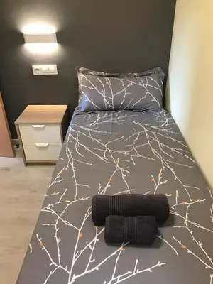 a bed with a black and white comforter on it at Cerdanyola centro in Cerdanyola del Valles