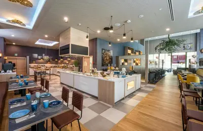 a restaurant with tables and chairs and a kitchen at Leonardo Royal Hotel Barcelona Fira in Barcelona