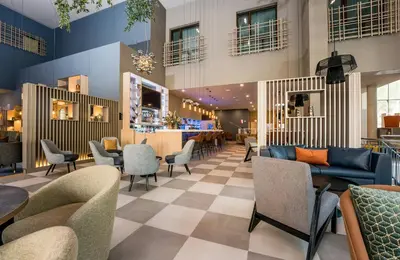 a lobby of a hotel with chairs and a bar at Leonardo Royal Hotel Barcelona Fira in Barcelona