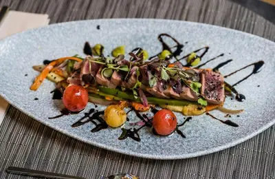 a plate of food with meat and vegetables on a table at Leonardo Royal Hotel Barcelona Fira in Barcelona