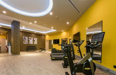 a gym with treadmills and exercise equipment in a room at Leonardo Royal Hotel Barcelona Fira in Barcelona