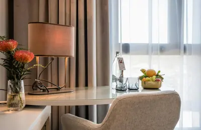 a desk with a lamp and a bowl of fruit on it at Leonardo Royal Hotel Barcelona Fira in Barcelona