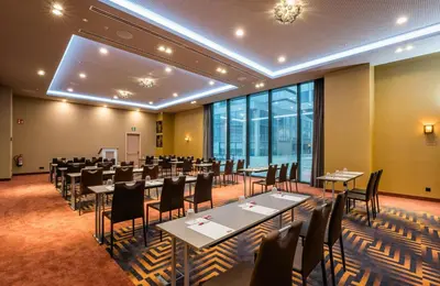 a banquet hall with tables and chairs in a room withwindows at Leonardo Royal Hotel Barcelona Fira in Barcelona