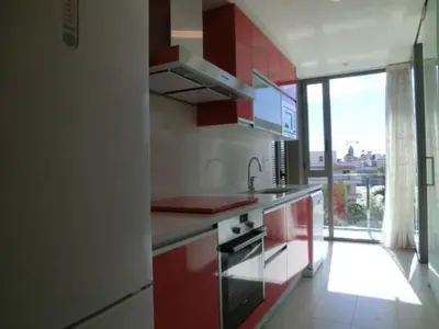 a kitchen with red and white cabinets and a window at Apartaments Can Negret in Sitges