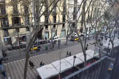 a busy city street with cars and people on the street at Hostal MiMi Las Ramblas in Barcelona