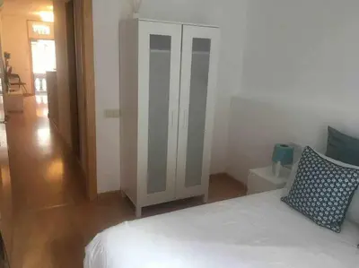 a bedroom with a white bed and a cabinet at Pretty Apartament in Barcelona
