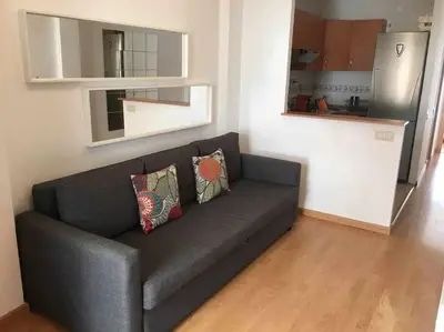 a black couch in a living room with a kitchen at Pretty Apartament in Barcelona