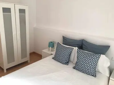 a bedroom with a white bed with blue pillows at Pretty Apartament in Barcelona