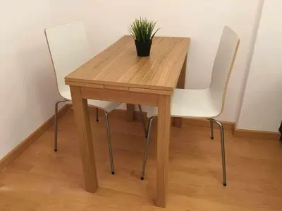 a wooden table with two white chairs and a potted plant at Pretty Apartament in Barcelona