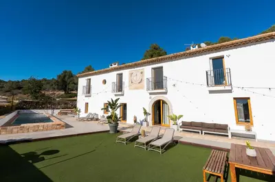 a large white building with chairs and a patio at Villa Masia Capdet in Sant Pere de Ribes