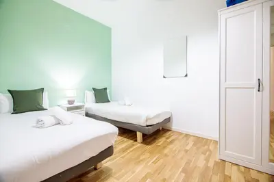 a bedroom with two beds and a door to a room at Be barcelona arco del triunfo sunny colors III in Barcelona