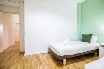 a bedroom with a bed with white sheets and green pillows at Be barcelona arco del triunfo sunny colors III in Barcelona