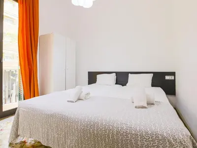 a bedroom with a large white bed with an orange curtain at Be barcelona arco del triunfo sunny colors in Barcelona