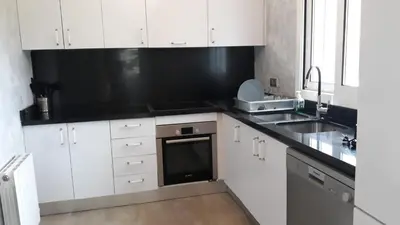 a kitchen with white cabinets and a black counter top at Edard's Private Villa in Castelldefels