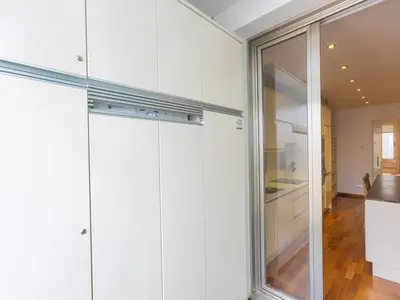 a kitchen with white cabinets and a sliding glass door at Apartment Centro- Passeig de Gracia - Casa Batllo by Interhome in Barcelona