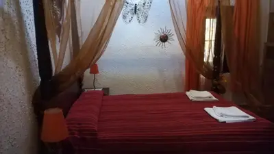 a bedroom with a bed with red sheets and white towels at Hostal Restaurante La Diligencia in Cunit