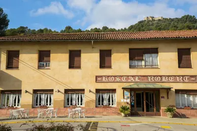 a building with tables and chairs in front of it at Hotel Robert in La Pobla de Claramunt