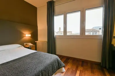a bedroom with a bed and a large window at Hotel Robert in La Pobla de Claramunt