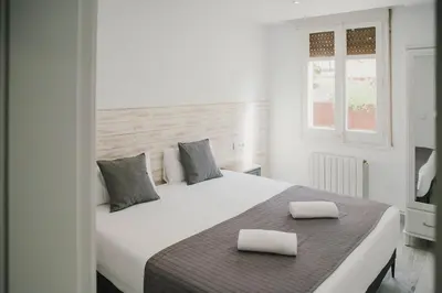 a bedroom with a white bed with two pillows on it at BBarcelona Fira Superior Flats in Barcelona