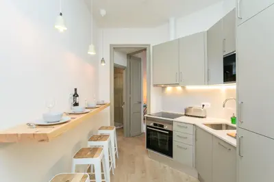 a kitchen with white cabinets and a counter with stools at Canela Homes BARCELONA MARINA in Barcelona