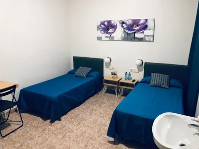 a room with two blue beds and a sink at Hostal Carlos III in El Prat de Llobregat