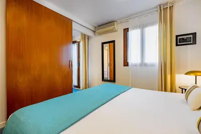 a bedroom with a white bed and a wooden cabinet at Lodging Apartments City Center-Eixample in Barcelona