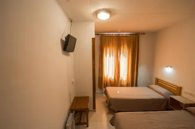 a room with two beds and a television and a window at Turó de L´Home in Santa María de Palautordera