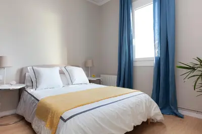 a bedroom with a bed with blue curtains and a window at My Address on the Beach and Sun in Barcelona