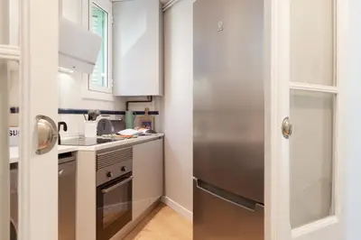 a kitchen with white cabinets and a stainless steel refrigerator at My Address on the Beach and Sun in Barcelona
