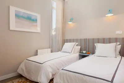 two beds in a room with white walls at My Address on the Beach and Sun in Barcelona