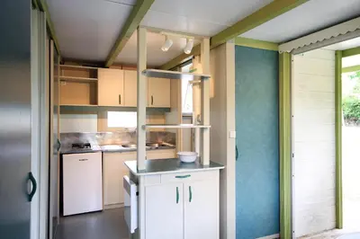 a kitchen with white cabinets and blue walls at Camping La Rueda in Cubelles