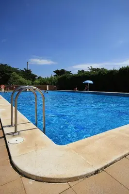 a swimming pool with blue water and a metal stairway at Camping La Rueda in Cubelles