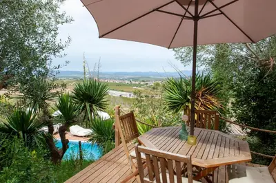 a wooden table with an umbrella on a deck at Cal Mestre Casa Rural in Avinyonet