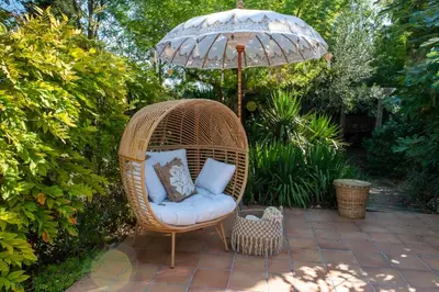 a wicker chair with an umbrella on a patio at Cal Mestre Casa Rural in Avinyonet